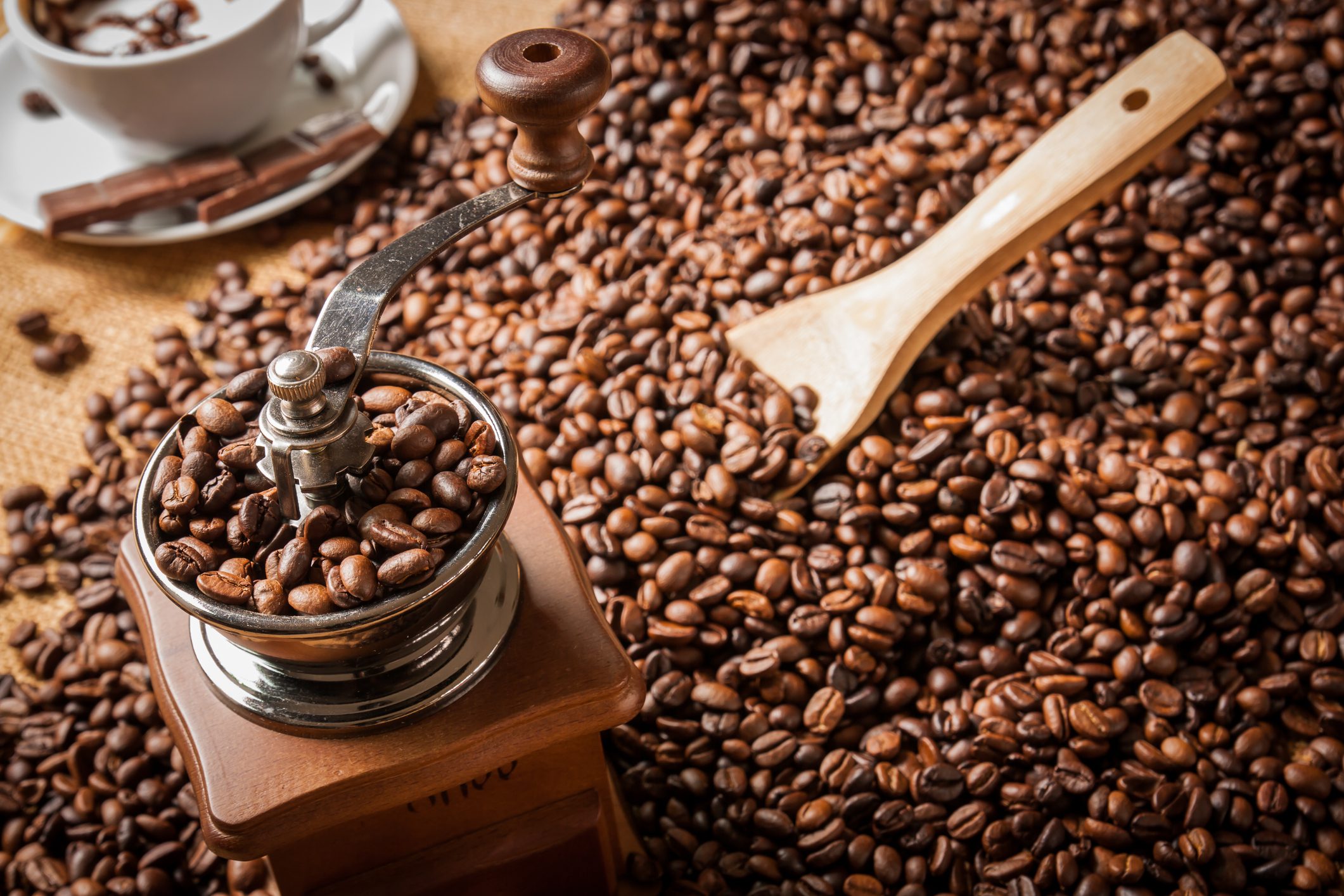 Manual coffee grinder with scattered coffee beans.