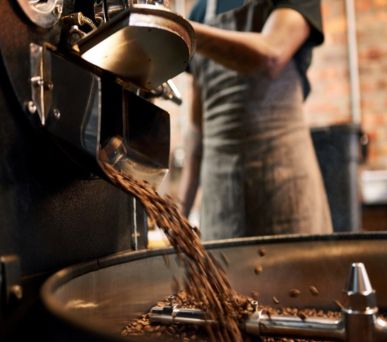 Close-up of coffee beans pouring from a roaster into a cooling tray.