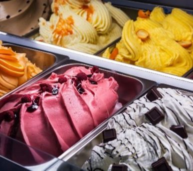 Colorful gelato flavors in metal trays ready to serve.