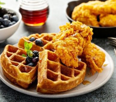 Crispy fried chicken served on golden waffles with syrup and blueberries.