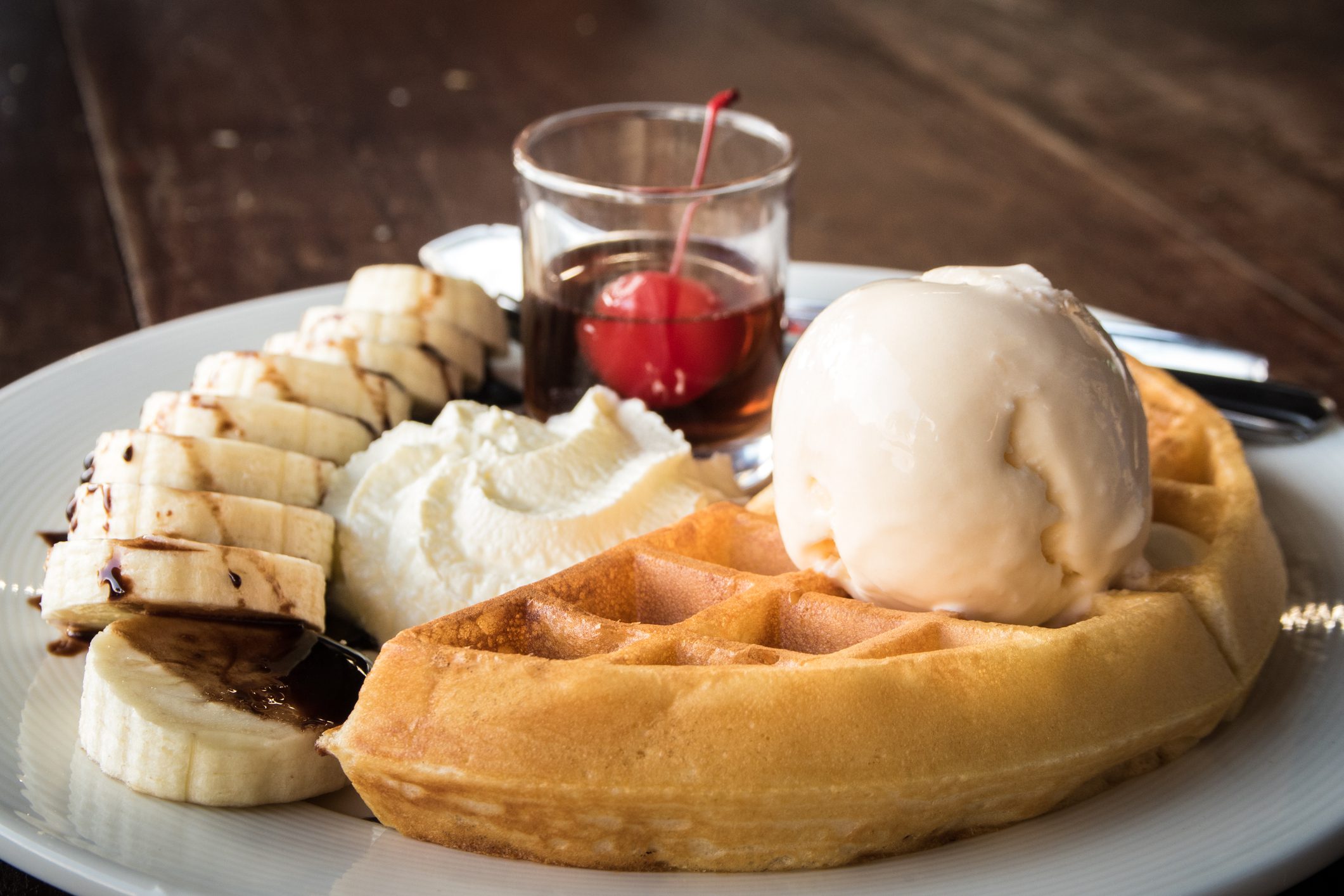 Waffle with ice cream, banana, and syrup.
