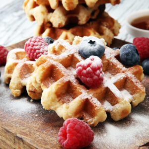 Freshly made waffles topped with powdered sugar and fresh berries.