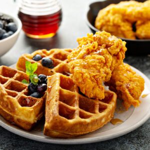 Crispy fried chicken served on golden waffles with syrup and blueberries.