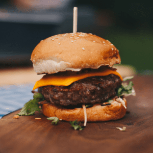 Juicy cheeseburger with lettuce on a wooden board.